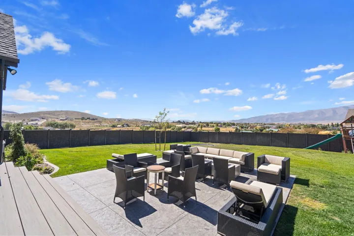 Expansive backyard featuring a large concrete patio, composite decking, and a manicured lawn