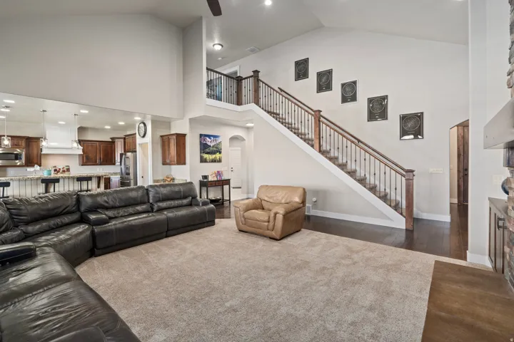 Vaulted ceilings define this open-concept living space, featuring a kitchen with a breakfast bar, stainless steel appliances, and wood cabinetry