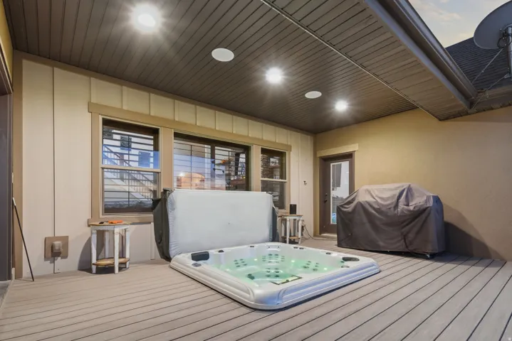 Covered outdoor deck with a recessed hot tub, composite decking, and overhead lighting