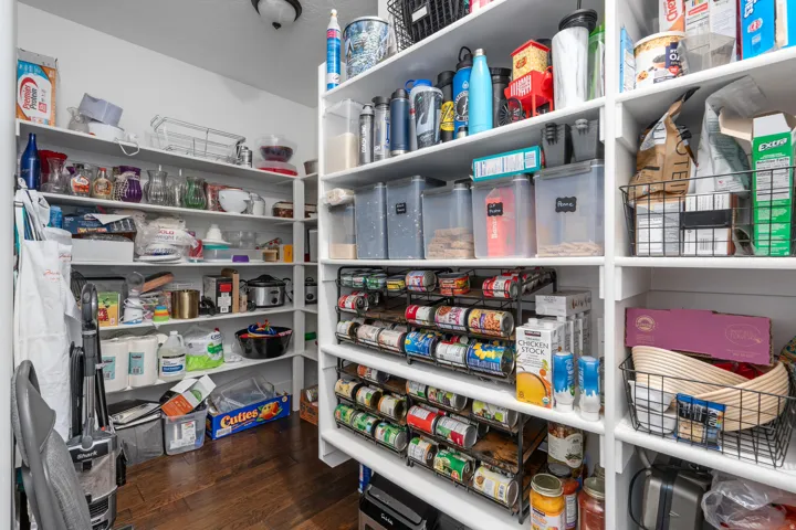 Expansive pantry with extensive built-in shelving, wood-finish flooring, and bright overhead lighting