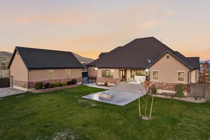 Expansive lawn area with a concrete patio, integrated fire pit, and a separate detached structure