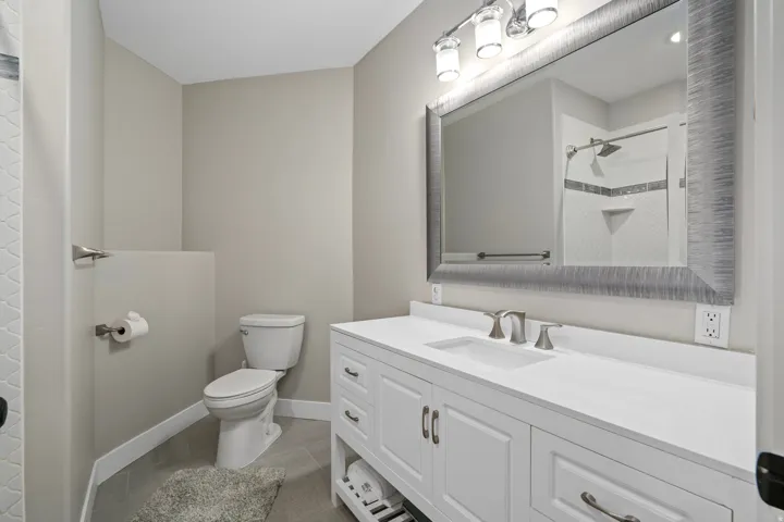 White vanity with brushed nickel hardware, white countertop, and single undermount sink