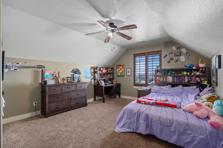 Carpeted flooring with a sloped ceiling and a ceiling fan