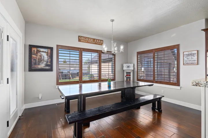 Wood-finish flooring, multiple windows with wood-frame plantation shutters, and a chandelier lighting fixture