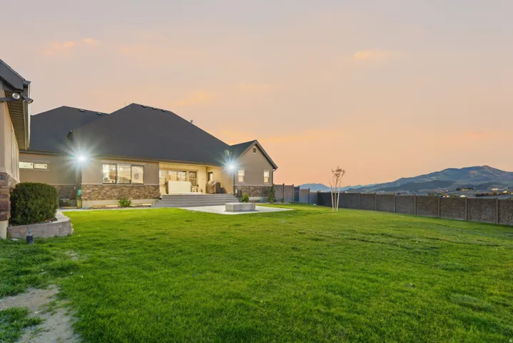 Expansive lawn with a concrete patio, built-in fire pit, and durable fencing