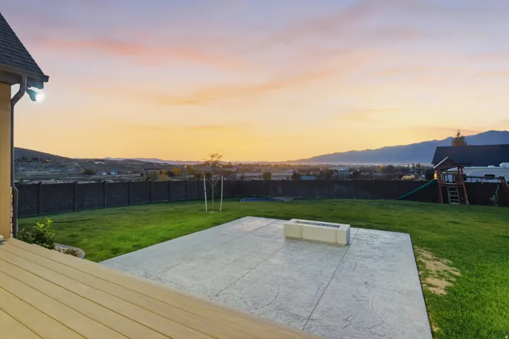 Large backyard featuring wood-finish decking, stamped concrete patio, and a built-in fire pit