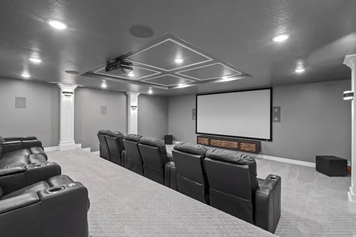 Dedicated media room featuring a large projector screen, recessed ceiling lighting, and decorative ceiling trim