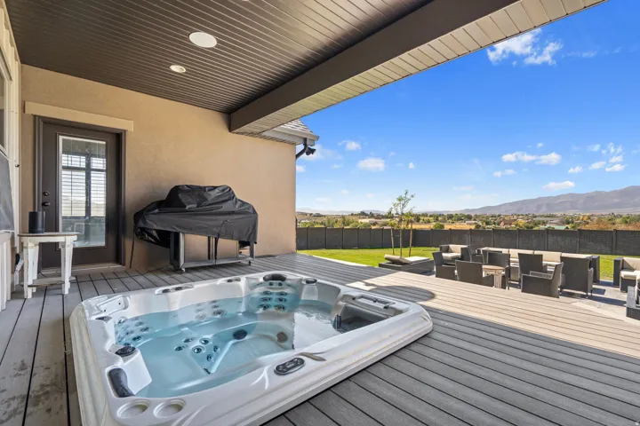 Expansive outdoor deck featuring a built-in hot tub, recessed lighting, and a broad overhead covering
