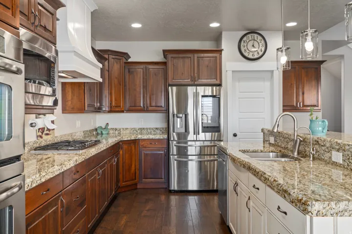 Kitchen featuring granite countertops, wood-finish flooring, stainless steel appliances, pendant lighting, and recessed ceiling lights