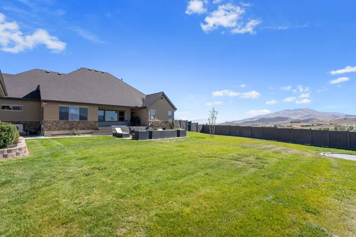 Expansive backyard with a manicured lawn, a large patio area, and a privacy fence