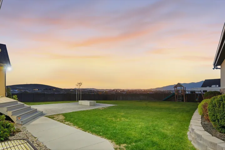 Expansive backyard featuring a manicured lawn, concrete patio, and a wood privacy fence