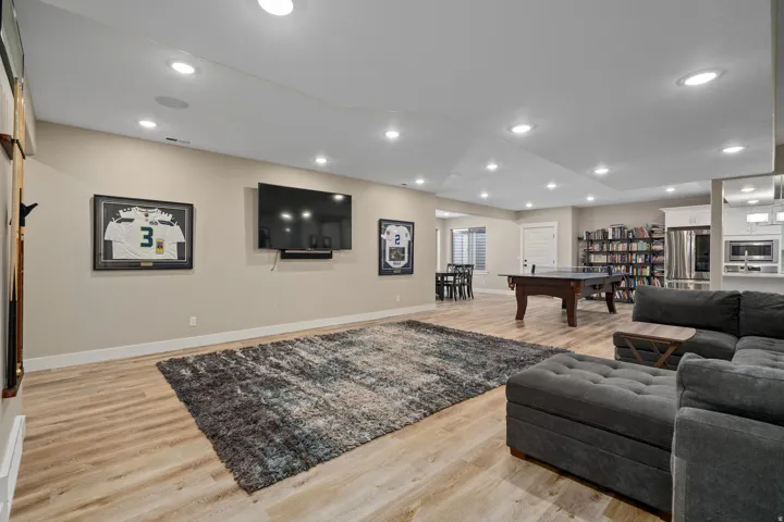 Recessed lighting, wood-finish flooring, built-in shelving, white cabinetry, and stainless steel appliances
