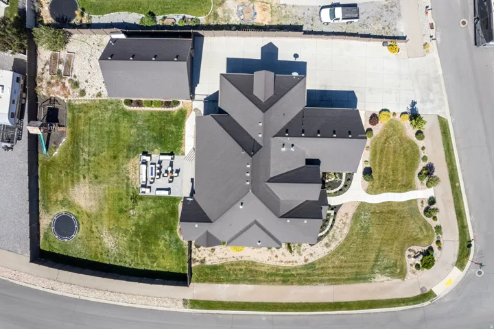 Expansive property featuring a multi-pitched roof, detached auxiliary building, paved driveway, and established landscaping