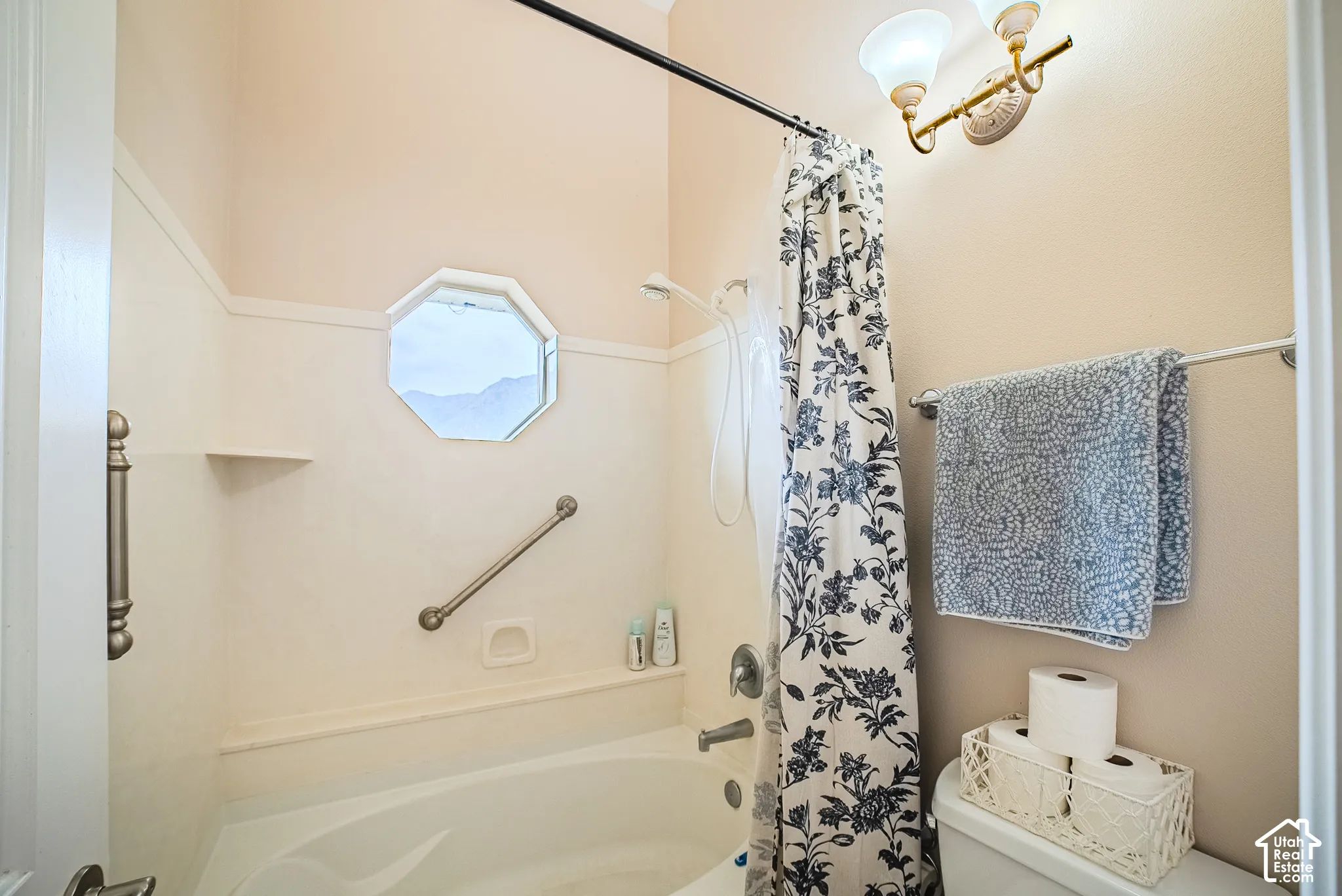 Bathtub with an octagonal window, grab bars, and a built-in shelf