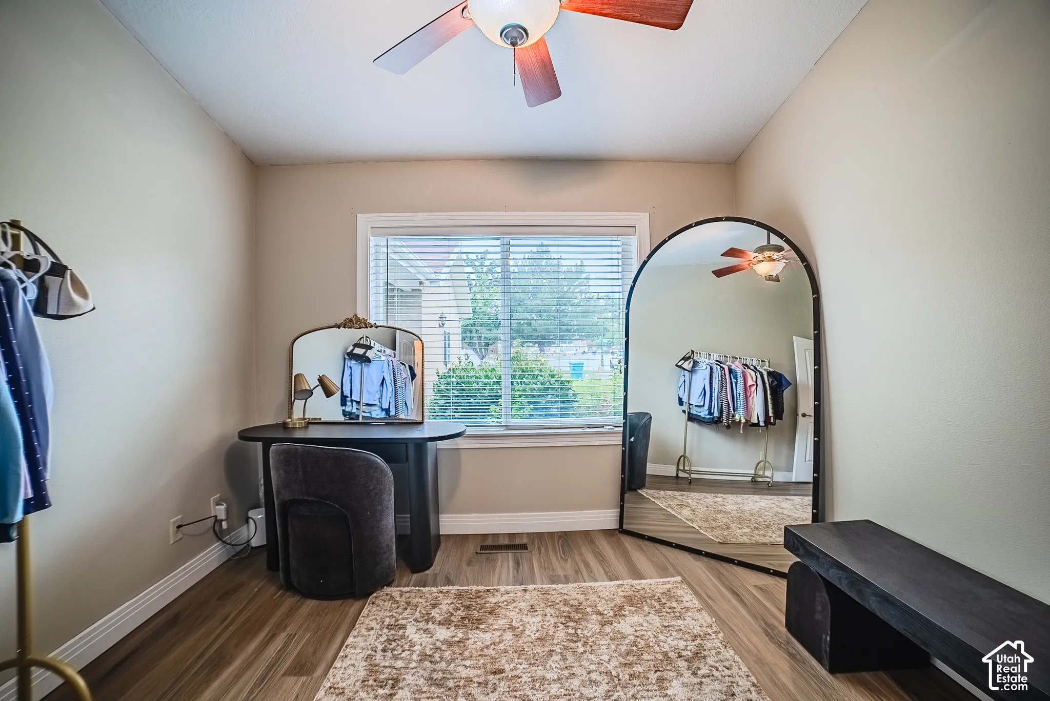 Wood-finish flooring, ceiling fan with integrated lighting, and a window with blinds providing natural illumination