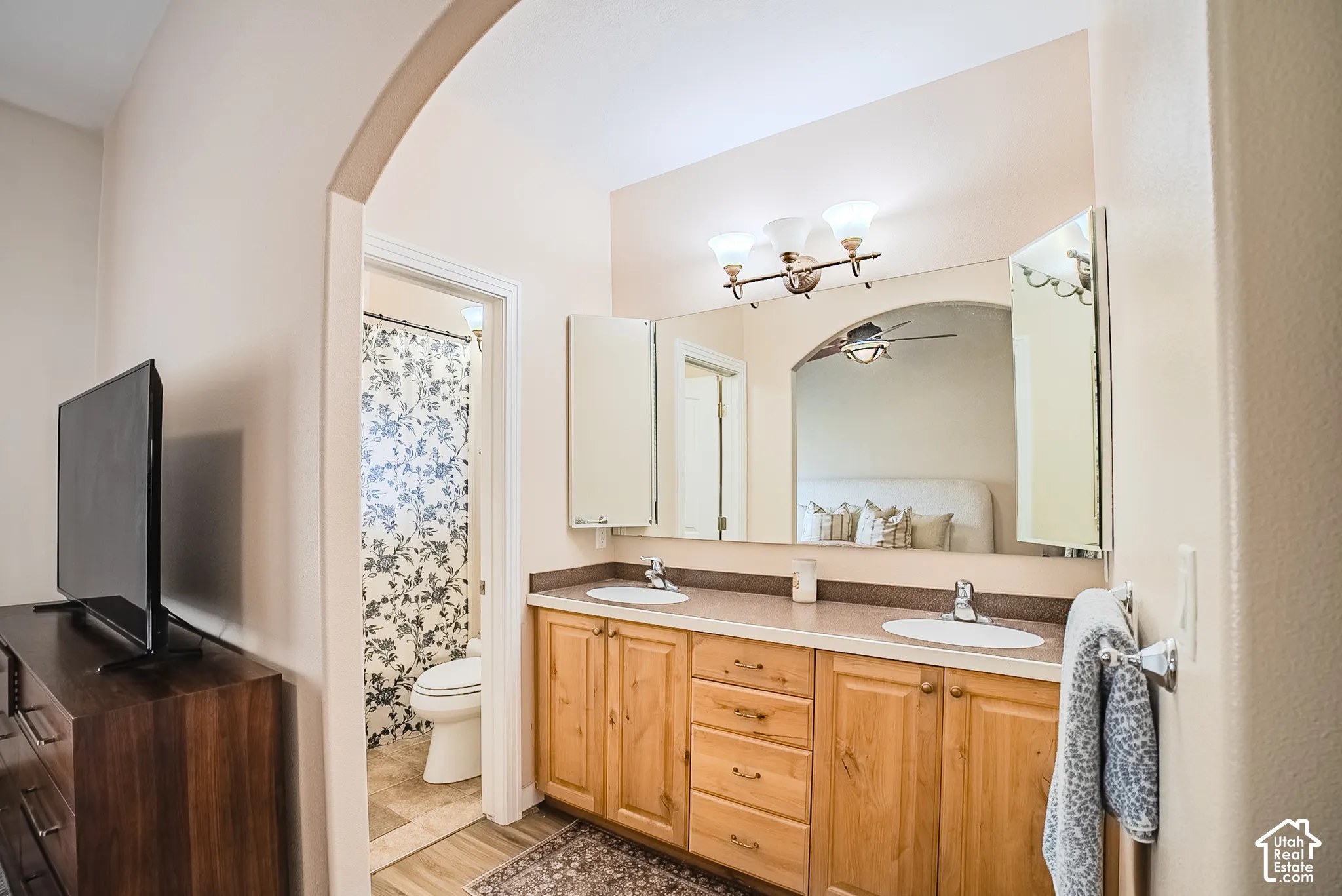 Dual vanity with wood-finish cabinetry, integrated sinks, and a framed mirror