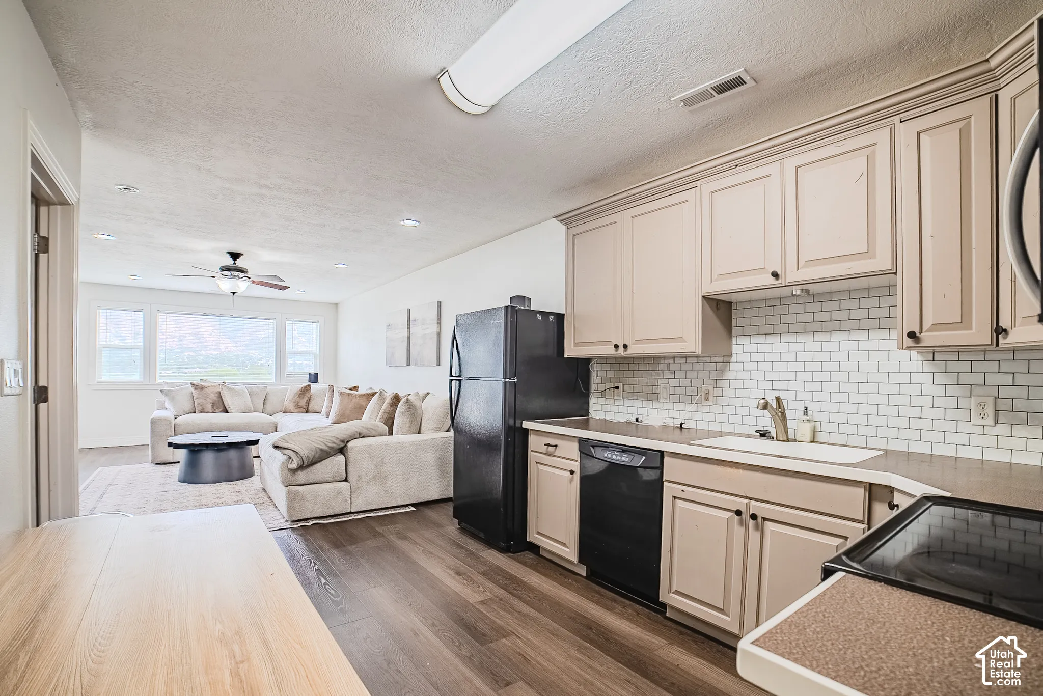 Kitchen featuring light-toned cabinetry, white subway tile backsplash, and dark countertops