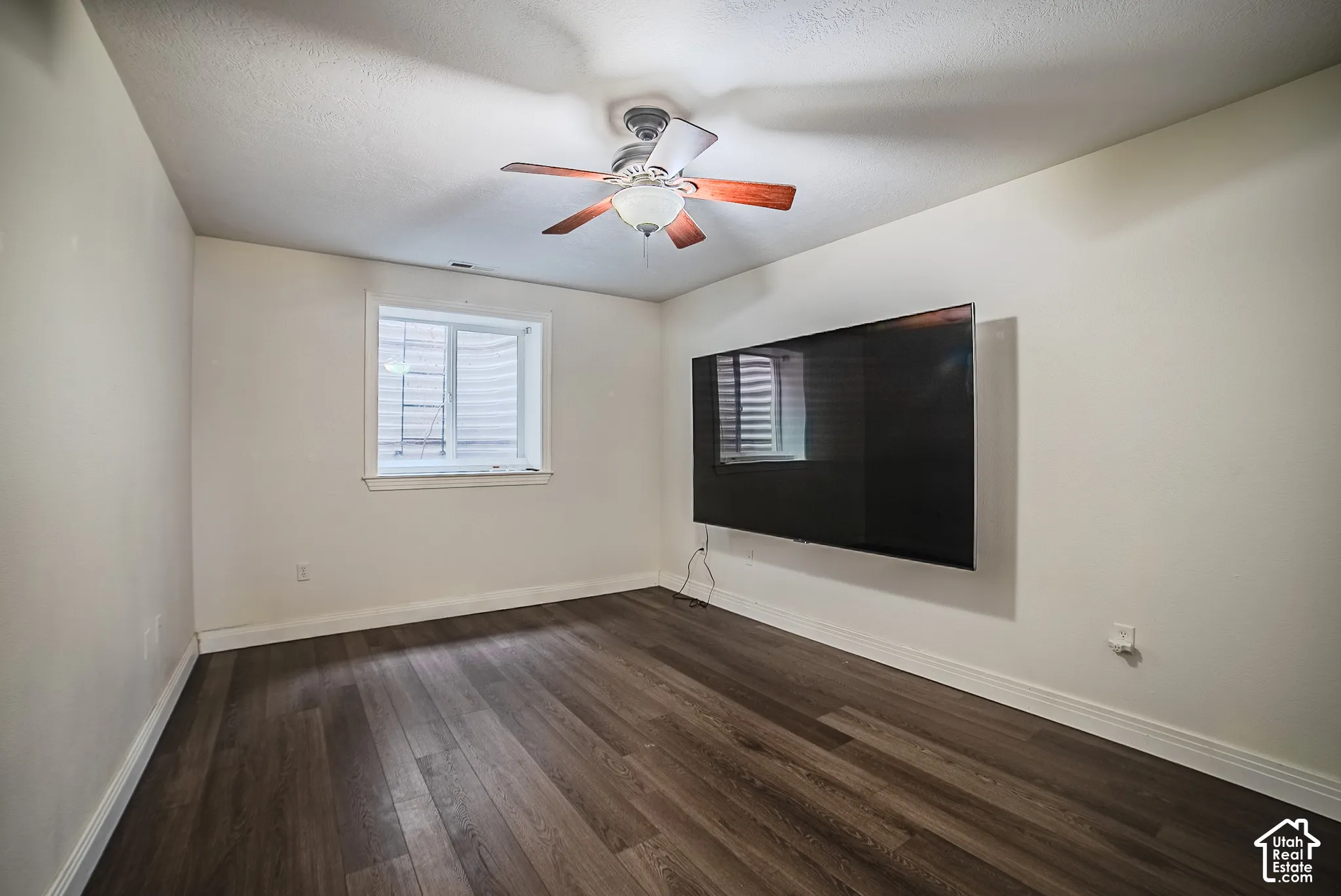 Wood-finish flooring, white walls, ceiling fan with light, and a window with blinds