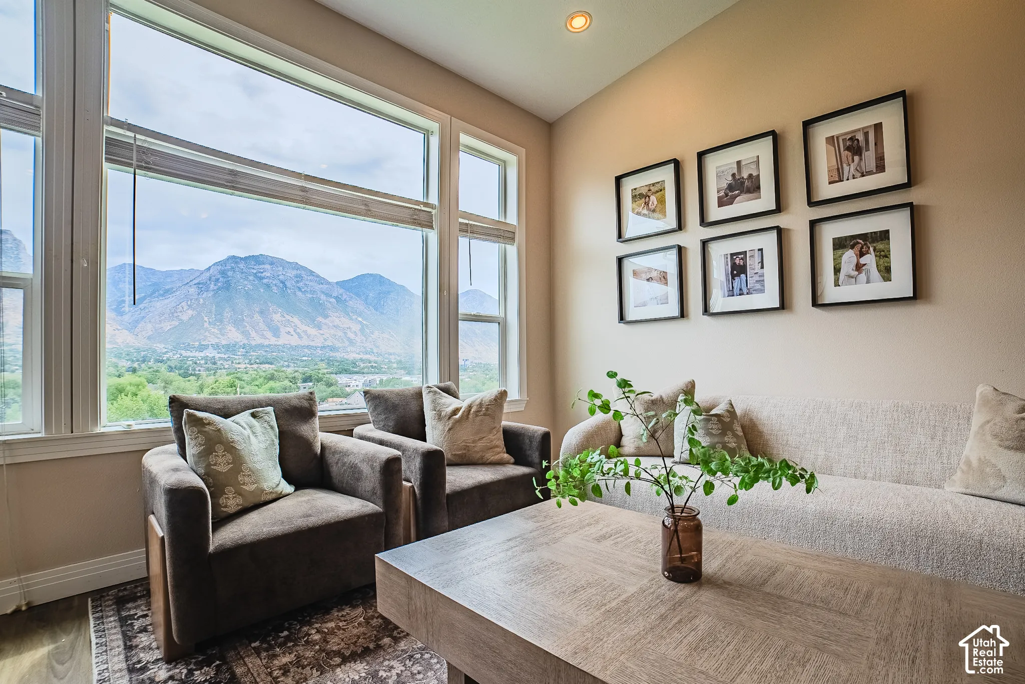Floor-to-ceiling windows with expansive mountain scenery, neutral wall tones, recessed lighting, and wood-finish flooring