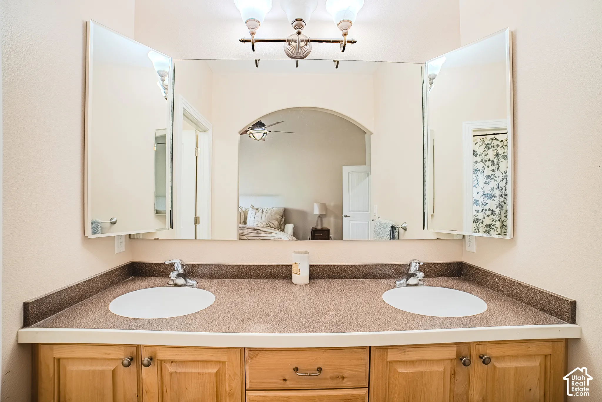 Double vanity with integrated sinks, wood-finish cabinetry, and a spacious wall-mounted mirror