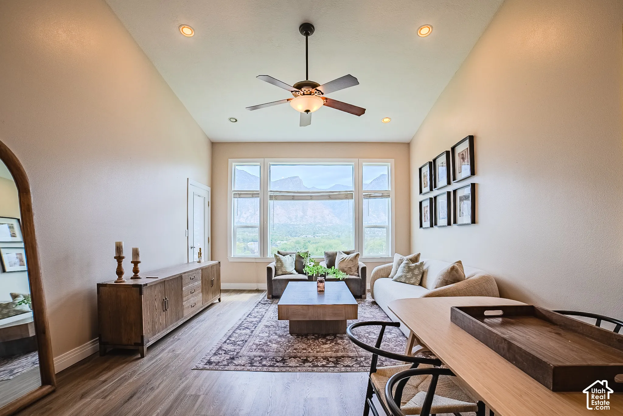 Vaulted ceilings with recessed lighting, wood-finish flooring, a ceiling fan, and large windows