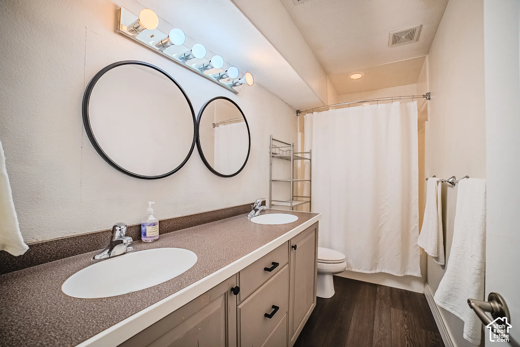Dual circular mirrors above a vanity with two integrated sinks