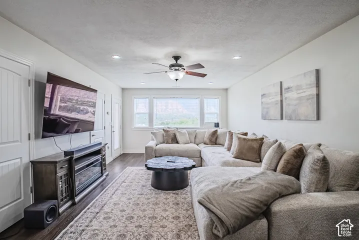 Recessed lighting throughout, ceiling fan with light fixture, multiple windows providing natural light, wood-finish flooring, and built-in media console with electric fireplace