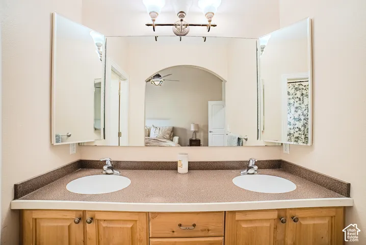 Double vanity with integrated sinks, wood-finish cabinetry, and a spacious wall-mounted mirror