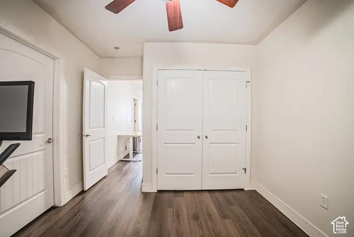 Wood-finish flooring, white paneled doors, ceiling fan with wood-tone blades, and a built-in closet with double doors