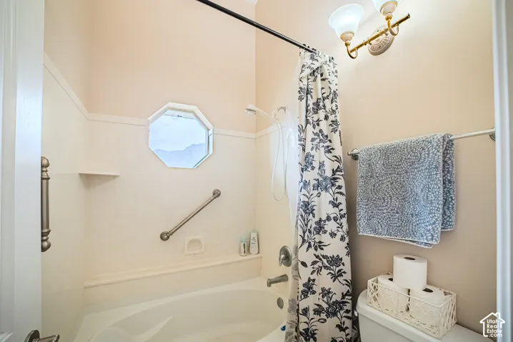 Bathtub with an octagonal window, grab bars, and a built-in shelf