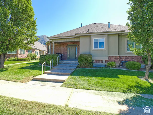 Brick and stucco exterior with a covered porch, concrete entry steps, and mature landscaping