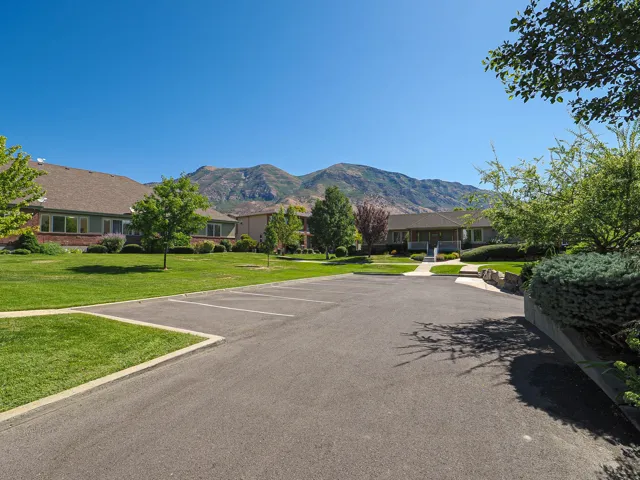 Sprawling circular driveway with mature landscaping, manicured lawn, and established trees framing the property