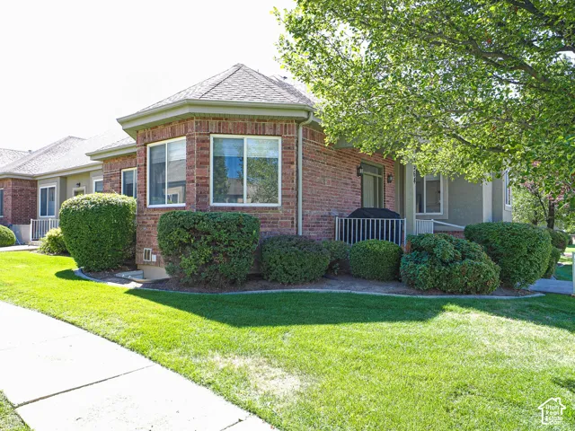 Brick exterior with multiple windows, a covered patio, and mature landscaping