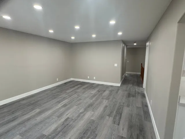 Recessed lighting, light gray wall paint, wood-finish flooring, and white trim