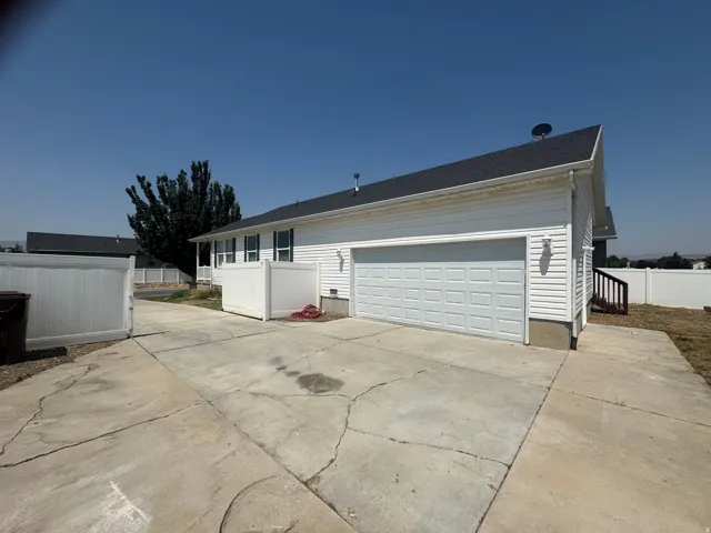 White siding exterior with a dark shingle roof, New attached garage with a new panel door, new opener and white privacy fencing
