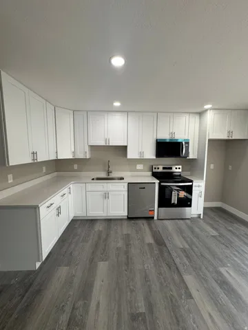 Kitchen featuring new LVP wood-finish flooring, recessed lighting, new white cabinetry, new light-toned quartz countertops, and new stainless-steel appliances