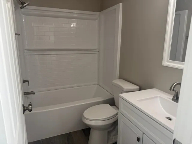 Primary Bathroom White subway tile shower surround with a built-in shelf, white vanity with an integrated sink, and brushed nickel fixtures