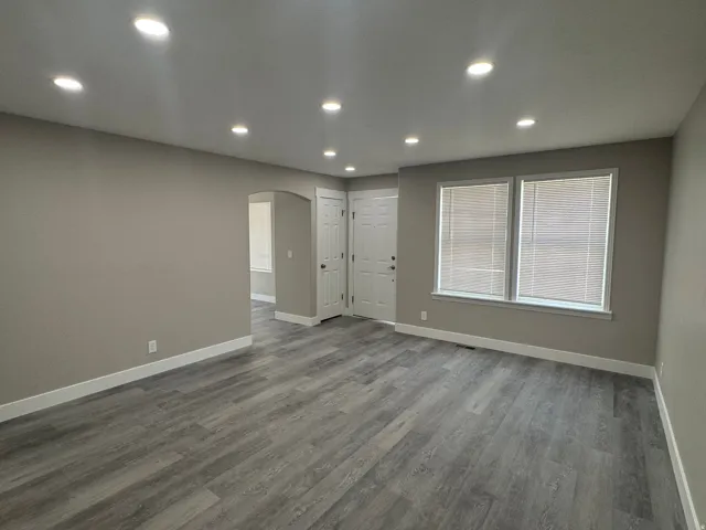 Recessed lighting, wood-finish flooring, neutral paint palette, white trim, and a white entry door