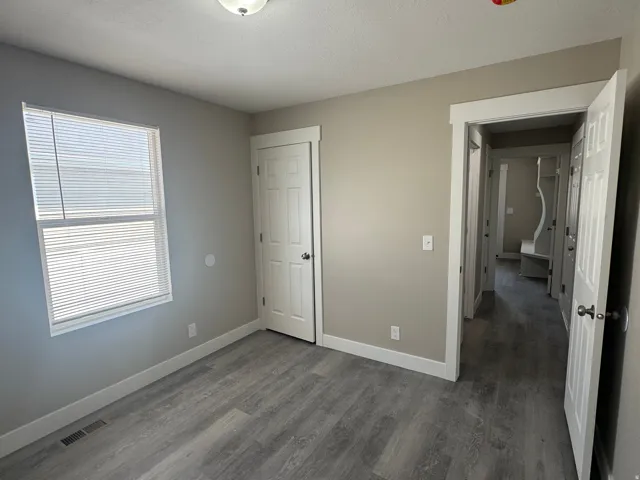 Neutral painted walls, wood-finish flooring, white trim, and a flush mount ceiling light