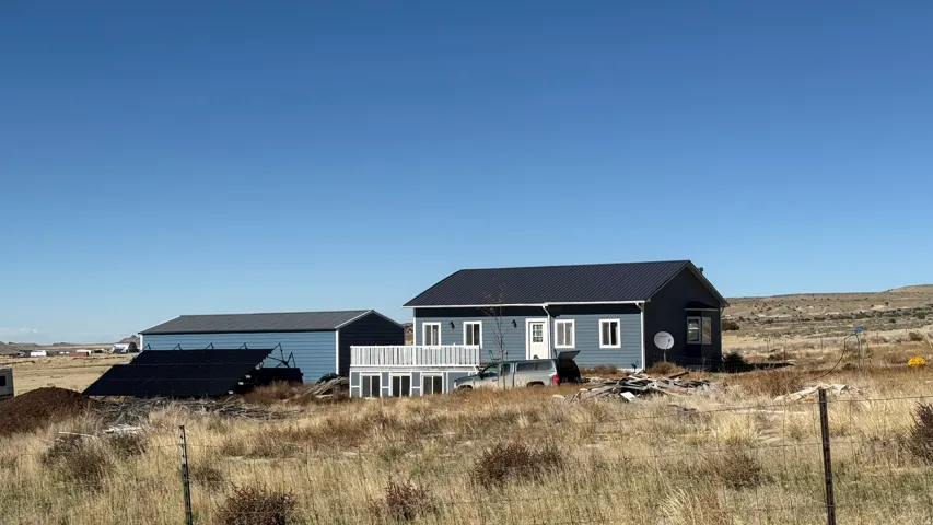Single-story residence with a dark metal roof, light blue siding, and white trim