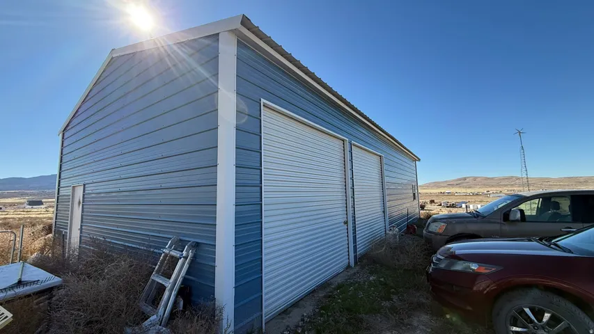 Metal outbuilding featuring dual roll-up doors, a side entry door, and a pitched roof