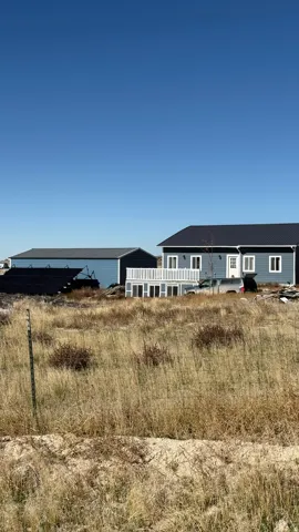 Blue exterior siding with white trim, dark roof, and a ground-level deck featuring white railings