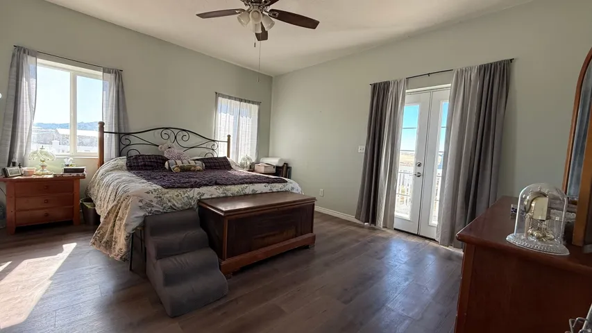 Expansive room featuring wood-finish flooring, a ceiling fan, and double French doors opening to an exterior space
