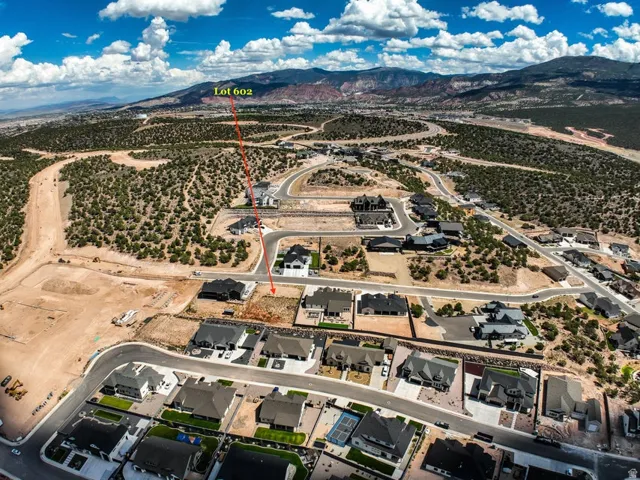 Expansive lot within a developed community, featuring surrounding residential properties and mountainous terrain