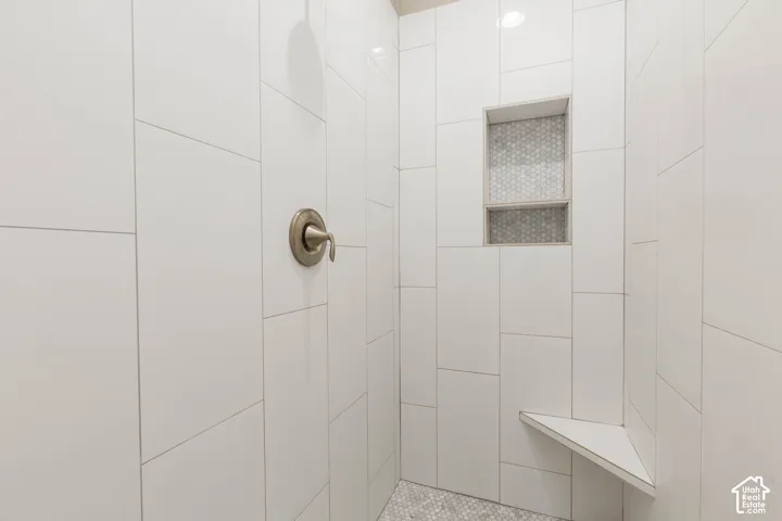 Primary Bathroom: Tiled walk-in shower with a built-in niche and corner bench