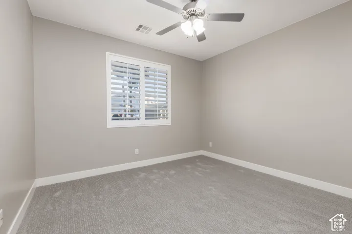 Bedroom: Main-floor bedroom with new carpet, plantation shutters, and a ceiling fan