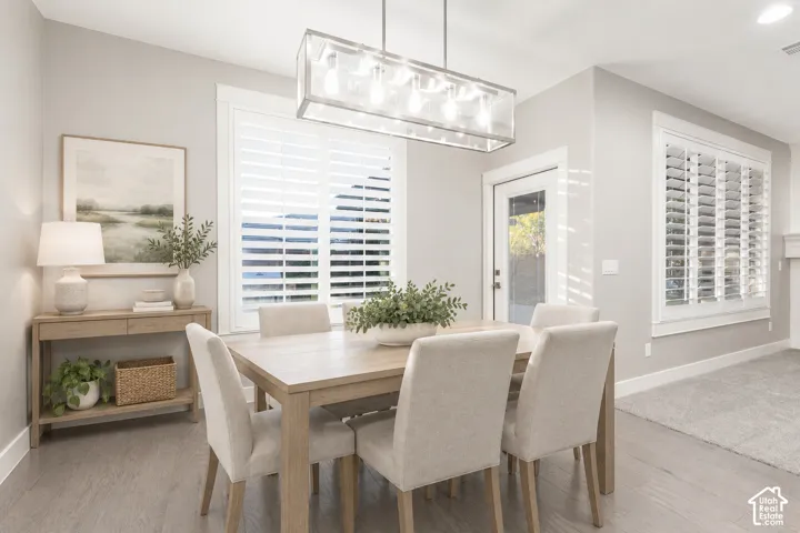 Dining Room: A linear glass chandelier, plantation shutters, and a door out to the covered patio