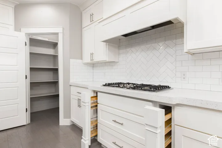Kitchen: Gas cooktop, herringbone tile backsplash, pull-out spice storage, and a pantry