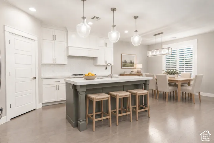 Kitchen: White shaker cabinetry, quartz counters, and a gray island under seeded-glass pendants