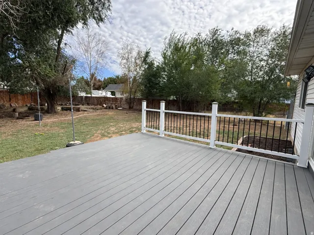 Expansive deck featuring gray composite decking and white railings with black balusters